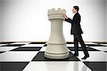 Businessman in suit pushing chess piece against white background with vignette