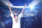 Cheering football fan in white against large football stadium with lights