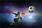 Football player in green kicking against black background with spark