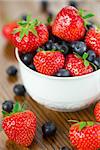 Bowl of strawberries and blueberries on a wooden table