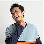 Young southeast Asian guy shaving his beard in a morning, on plain background