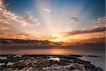 Rocky Beach and Sky with Sunrays on Cloudy Morning