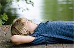 Young boy dreaming the day away on a dock