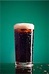glass of cola with foam on green background