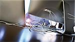 Close-up of man working at desk with backview of computers and assorted wires, Canada