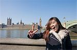 Portrait of young woman gesturing V-sign against Big Ben at London, England, UK