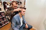 Barber shaving male customer's hair in shop