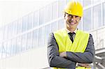 Portrait of smiling young male architect standing arms crossed outside office building