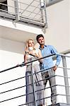 Smiling young man with woman having coffee at hotel balcony