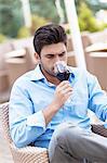 Young man drinking red wine at outdoor restaurant