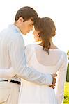 Rear view of romantic couple standing arms around against clear sky