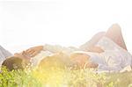 Young couple lying on grass against clear sky