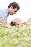 Side view of young man looking at woman sleeping on grass