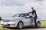 Full length of young businessman reading map by car at countryside