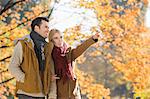 Woman pointing while standing with man in park during autumn