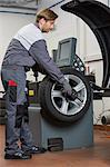 Side view of male mechanic repairing car's wheel in workshop