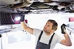 Male repair worker examining car in workshop