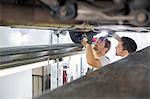 Maintenance engineers repairing car in workshop