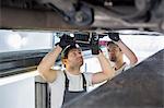 Maintenance engineers repairing car in workshop