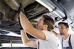 Male repair workers examining car in workshop