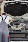 Rear view of male engineer repairing car in automobile repair shop