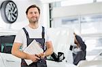 Portrait of confident male maintenance engineer with clipboard in car repair shop