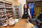 Portrait of young saleswoman standing at cash counter in supermarket