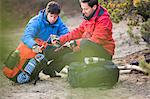 Male backpackers looking at rope in forest