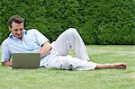 Full length of young man using laptop while lying on grass in park