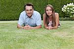 Portrait of happy young couple lying on grass in park