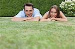 Portrait of smiling young couple relaxing on grass in park