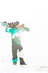 Full length of young man carrying snowboard in snow