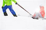 Low section of man giving sled ride to woman in snow