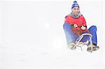 Full length of young woman sledging in snow