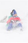 Cheerful young couple sledding in snow