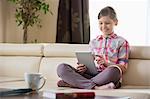 Smiling girl using digital tablet on sofa at home