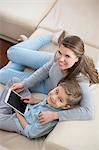 High angle portrait of mother and son with tablet PC sitting on sofa