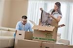 Mid-adult couple unpacking cardboard boxes in new home