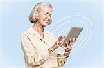 Happy senior businesswoman using tablet PC against clear blue sky