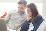 Couple relaxing at home looking at laptop computer together