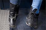 Women sitting together on subway train, close-up of boots