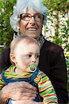 Grandmother holding young grandson on lap outdoors