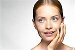 Young woman applying moisturizer to face