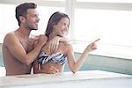 Couple wading in indoor pool looking at view through window