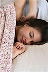 Woman relaxing in bed, cropped