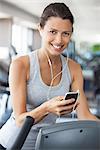 Young woman listening to music while using step climber at gym