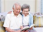 senior asian couple reading a book together at home.