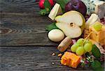 Delicious cheese and fruits on a wooden board. Food ingredients background. Selective focus.