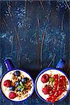 Yogurt with granola and fresh berries on an old wooden board.