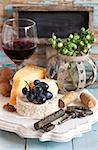 Still life with delicious cheese, red wine, fruits and nuts.